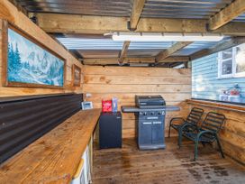 An outdoor kitchen with a grill and chairs at Taylor Lodge Adventure Base - Erua Holiday Home National Park