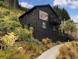 A house with a balcony and landscaped garden at Alpine Luxe - Queenstown Holiday Home in Queenstown