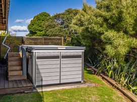 A hot tub beside wooden stairs in a garden at Coastal Serenity - Te Tii Escape