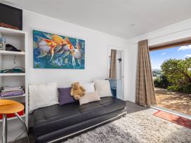 A living room with a sofa and artwork at Coastal Serenity - Te Tii Escape