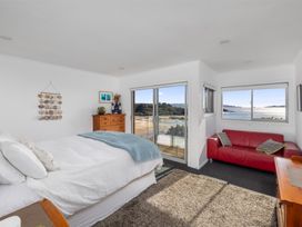 A bedroom with a bed and a sofa at Coastal Serenity - Te Tii Escape