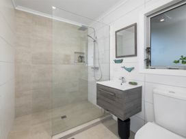 A bathroom with a shower, toilet, and vanity at Coastal Serenity - Te Tii Escape
