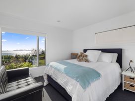 A bedroom with a bed and sofa at Coastal Serenity - Te Tii Escape