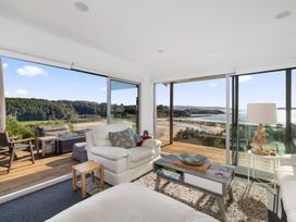 A living room with large glass doors and a view at Coastal Serenity - Te Tii Escape