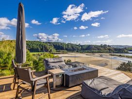 An outdoor seating area with a fire pit and chairs at Coastal Serenity - Te Tii Escape