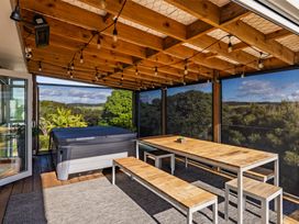 An outdoor dining area with a hot tub and wooden table at Coastal Serenity - Te Tii Escape