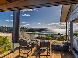 An outdoor seating area with chairs and a table overlooking the water at Coastal Serenity - Te Tii Escape