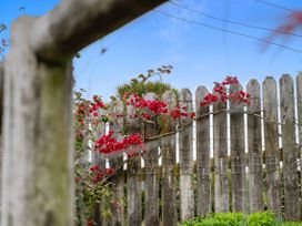 A garden with a wooden fence and red flowers at Raglan Holiday Home Raglan