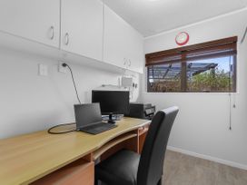 An office with a desk and laptop at Raglan Holiday Home in Raglan