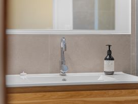 A sink with a faucet and soap dispenser at Raglan Holiday Home in Raglan