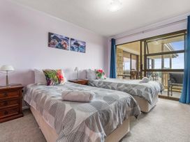 A bedroom with two single beds and a large window at Raglan Holiday Home in Raglan