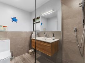 A bathroom with a shower and washbasin at Raglan Holiday Home in Raglan