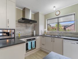 A kitchen with cabinets, sink, and appliances at Raglan Holiday Home in Raglan