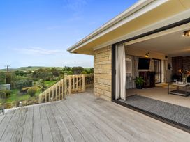 A balcony with glass railing and access to living room at Raglan Holiday Home in Raglan