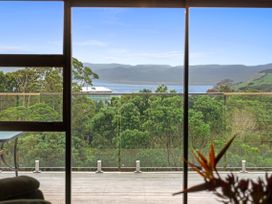 A living room with a view of trees and mountains at Raglan Holiday Home in Raglan