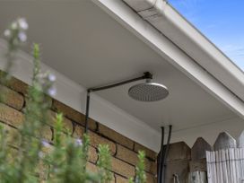An outdoor shower head mounted under the roof at Raglan Holiday Home in Raglan