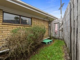 An outdoor area with a bush and green platform at Raglan Holiday Home in Raglan