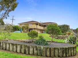 A house with a balcony and garden at Raglan Holiday Home in Raglan