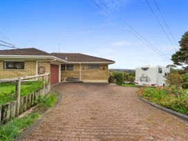 An outdoor view of a house with a driveway and a caravan at Raglan Holiday Home, Raglan