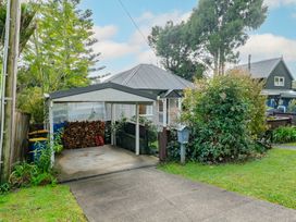 An outdoor space with a carport and firewood storage at Birdsong Retreat - Titirangi Holiday Home, Auckland