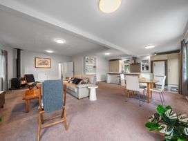 A living room with a sofa, dining table, and kitchen at Birdsong Retreat - Titirangi Holiday Home Auckland