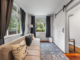 A living room with a sofa and window at Birdsong Retreat - Titirangi Holiday Home Auckland