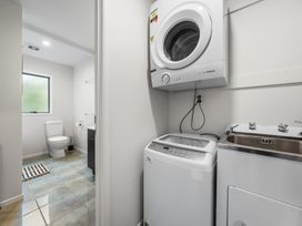 A laundry room with a washing machine and dryer at Birdsong Retreat - Titirangi Holiday Home Auckland