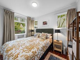 A bedroom with a bed and bedside table at Birdsong Retreat - Titirangi Holiday Home in Auckland