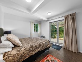 A bedroom with a bed and window at Birdsong Retreat - Titirangi Holiday Home Auckland