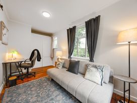 A living room with a sofa and desk at Birdsong Retreat - Titirangi Holiday Home Auckland