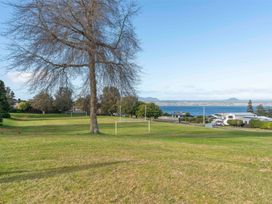 An outdoor area with a tree and field near a lake at The Cozy Corner - Taupo Holiday Home Acacia Bay