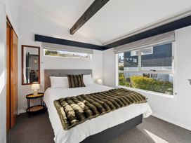 A bedroom with a bed, lamp, and window at The Cozy Corner - Taupo Holiday Home Acacia Bay