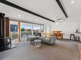 A living room with a sofa and dining area at The Cozy Corner - Taupo Holiday Home, Acacia Bay