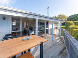 An outdoor seating area with a table and glasses at The Cozy Corner - Taupo Holiday Home in Acacia Bay