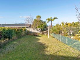 A garden with grass, trees, and a fence at The Cozy Corner - Taupo Holiday Home in Acacia Bay