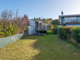 A garden with two houses and grass at The Cozy Corner - Taupo Holiday Home Acacia Bay