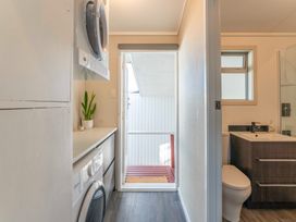 A bathroom with a washing machine, sink, and toilet at The Cozy Corner - Taupo Holiday Home, Acacia Bay