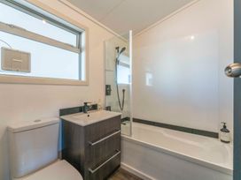 A bathroom with a sink, toilet, shower, and bathtub at The Cozy Corner - Taupo Holiday Home in Acacia Bay