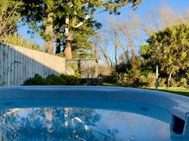 A hot tub with a wooden fence and trees in the background at Alpine Basecamp - Ohakune