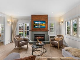 A living room with a fireplace and armchairs at Board and Batten - Matakana Holiday Home, Matakana