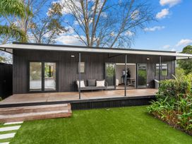 An outdoor view of a house with a deck and grass area at Board and Batten - Matakana Holiday Home Matakana