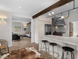 A kitchen with bar stools and kitchen appliances at Board and Batten - Matakana Holiday Home, Matakana