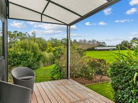 An outdoor area with a chair and garden at Board and Batten - Matakana Holiday Home in Matakana