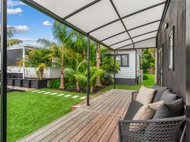 An outdoor seating area with a sofa and palm trees at Board and Batten - Matakana Holiday Home, Matakana