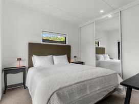 A bedroom with a bed and nightstand at Board and Batten - Matakana Holiday Home in Matakana