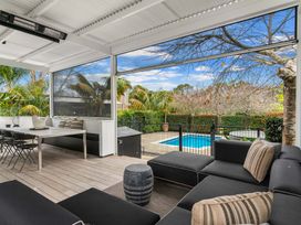 An outdoor area with seating, dining table, and a swimming pool at Board and Batten - Matakana Holiday Home, Matakana