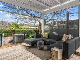 An outdoor living area with a sectional sofa and hot tub at Board and Batten - Matakana Holiday Home in Matakana