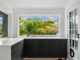 A kitchen with a window overlooking palm trees at Board and Batten - Matakana Holiday Home