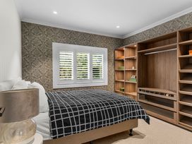 A bedroom with a bed and built-in wardrobe at Board and Batten - Matakana Holiday Home in Matakana