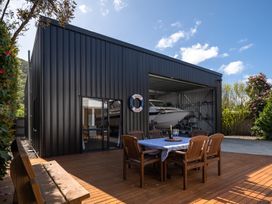 An outdoor area with a table and chairs near a building storing a boat at Bayview Haven - Waikawa Retreat, Picton